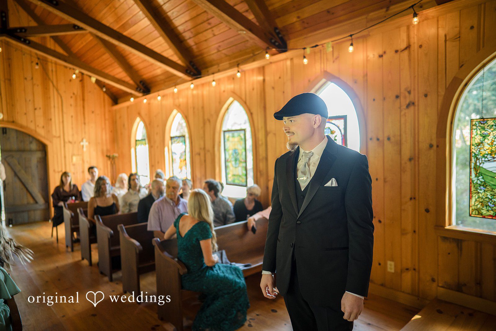 Jade + Nicholas A groom walking down a church aisle flanked by seated guests.
