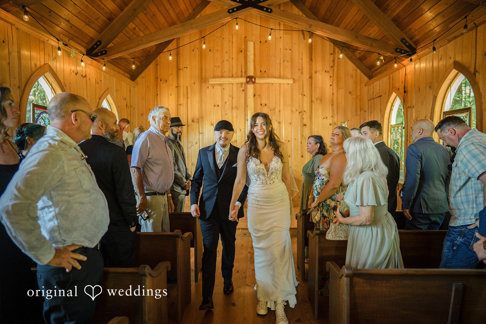 Jade + Nicholas Wedding guests standing and watching a ceremony inside a rustic church.