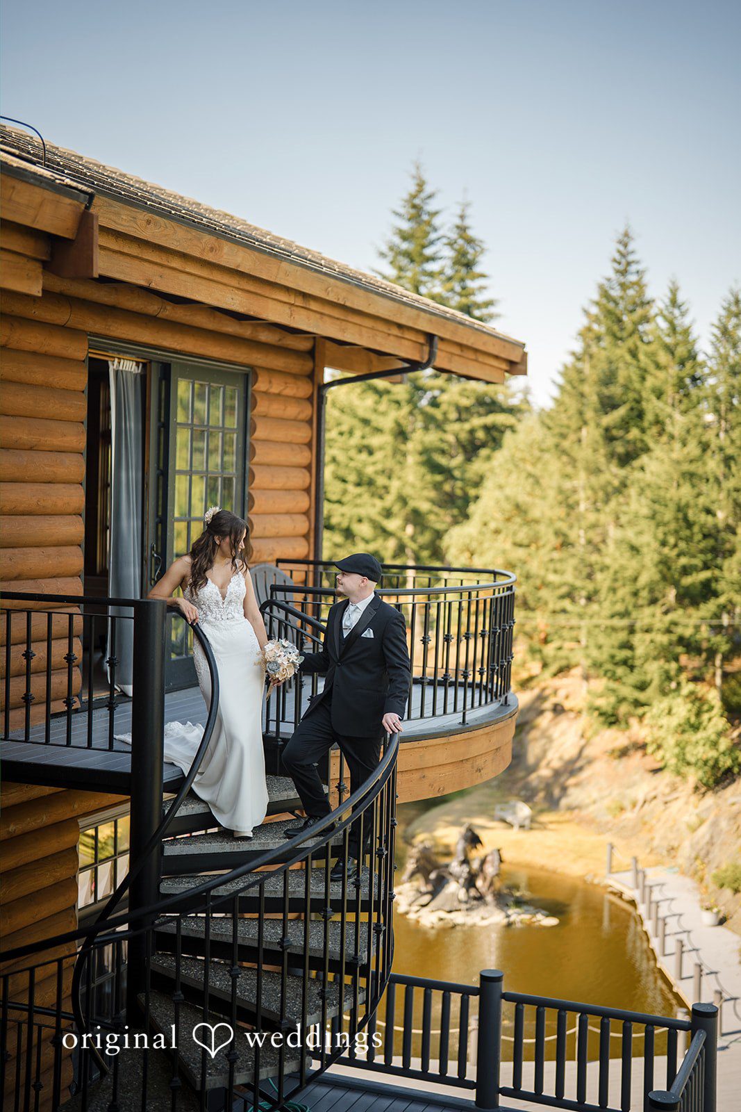 Jade + Nicholas A bride and groom standing together on the balcony steps of a rustic log cabin.