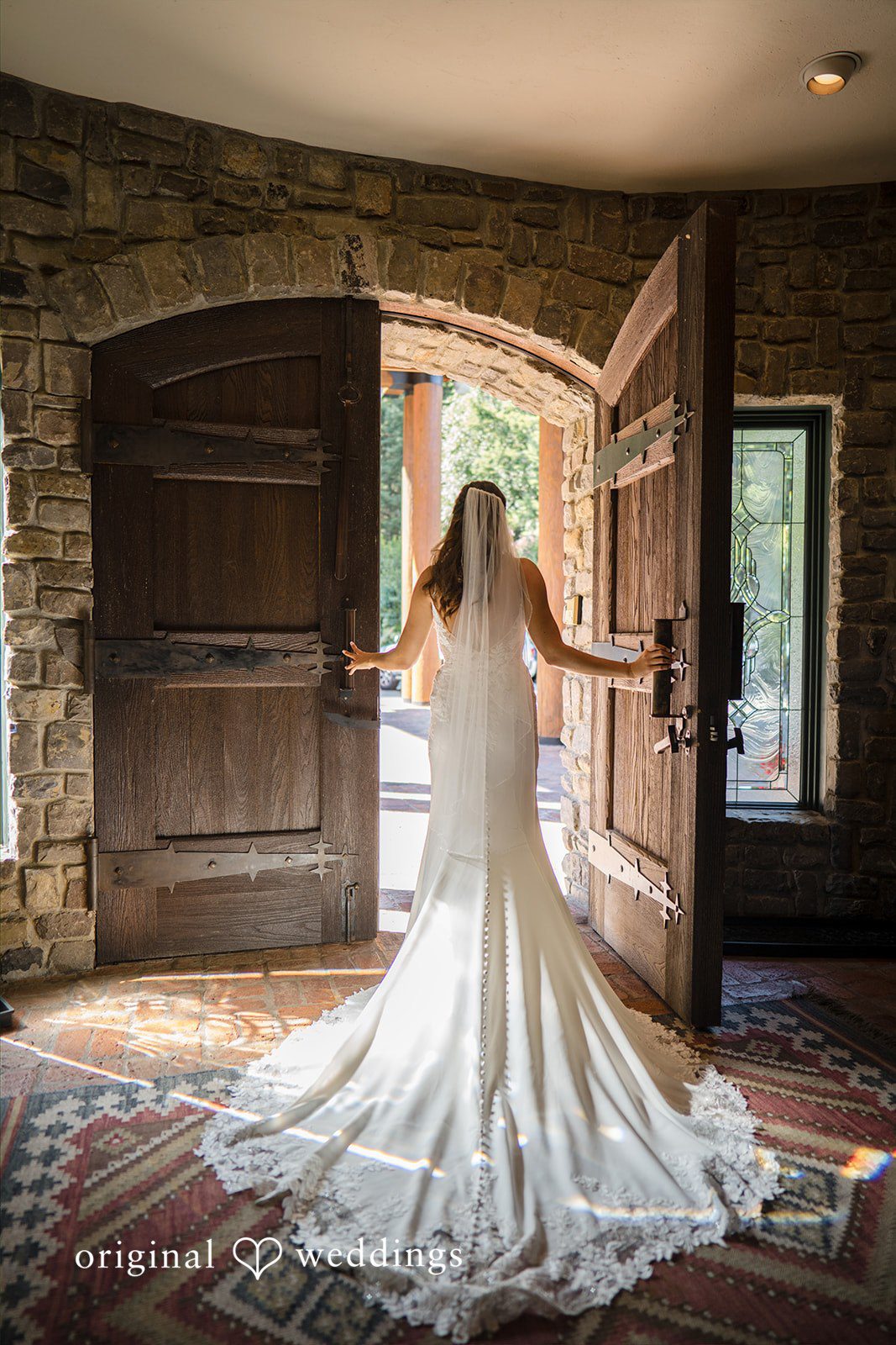Jade + Nicholas A bride in a flowing wedding gown facing an open wooden doorway.