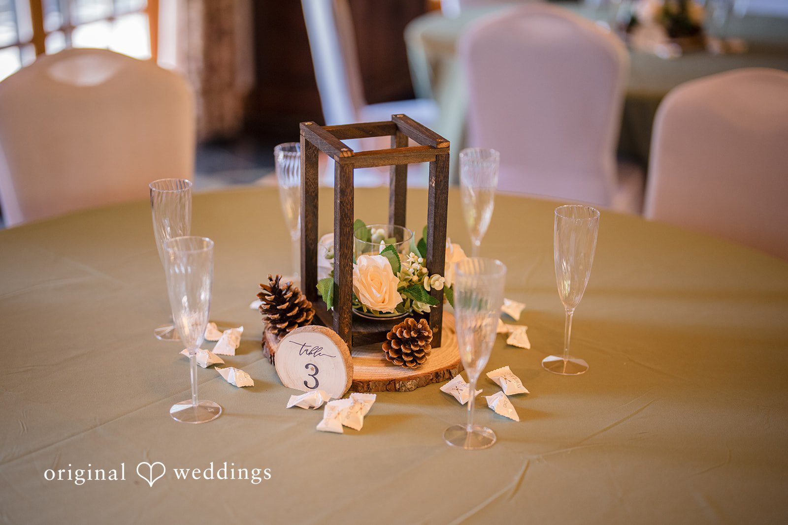 Jade + Nicholas A decorative centerpiece featuring a lantern surrounded by small flowers on a table.