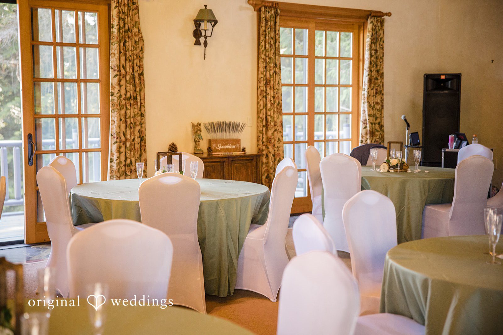 Jade + Nicholas A banquet hall arranged with round dining tables and white fabric-draped chairs.