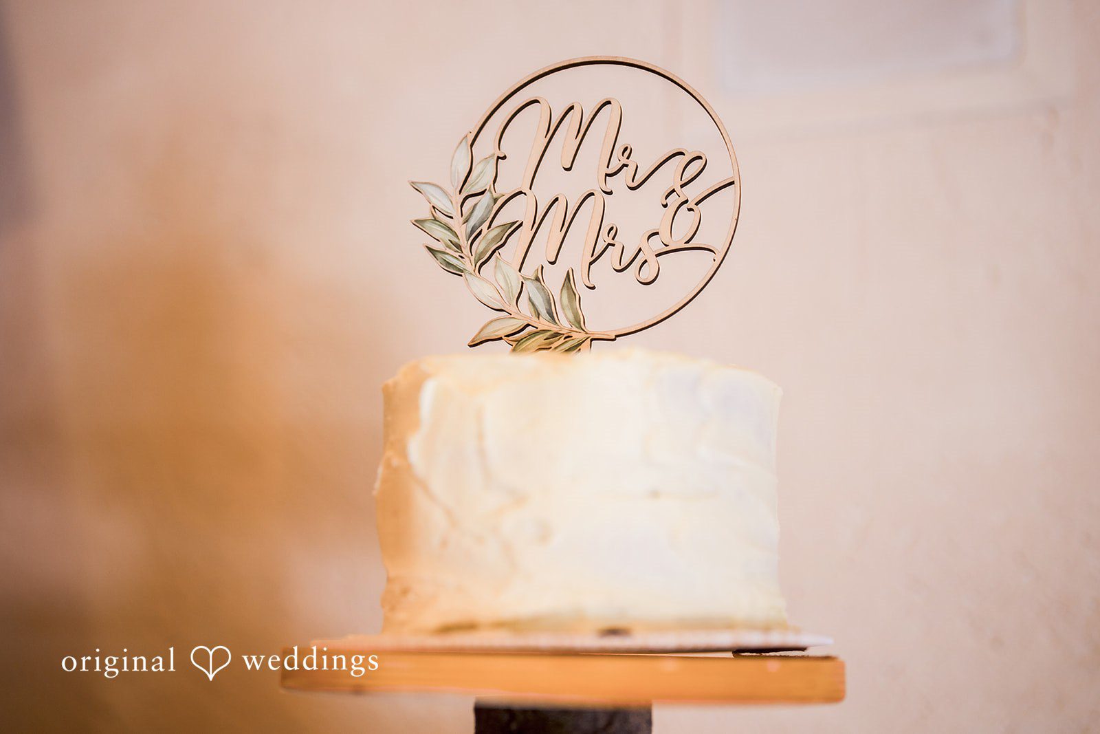 Jade + Nicholas A tiered wedding cake with a decorative custom topper.