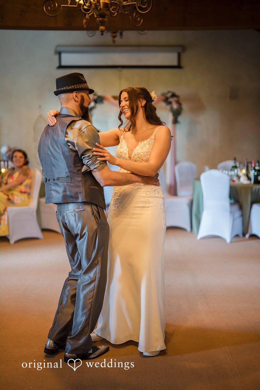Jade + Nicholas A bride and wedding guest dancing together closely while surrounded by a reception room.