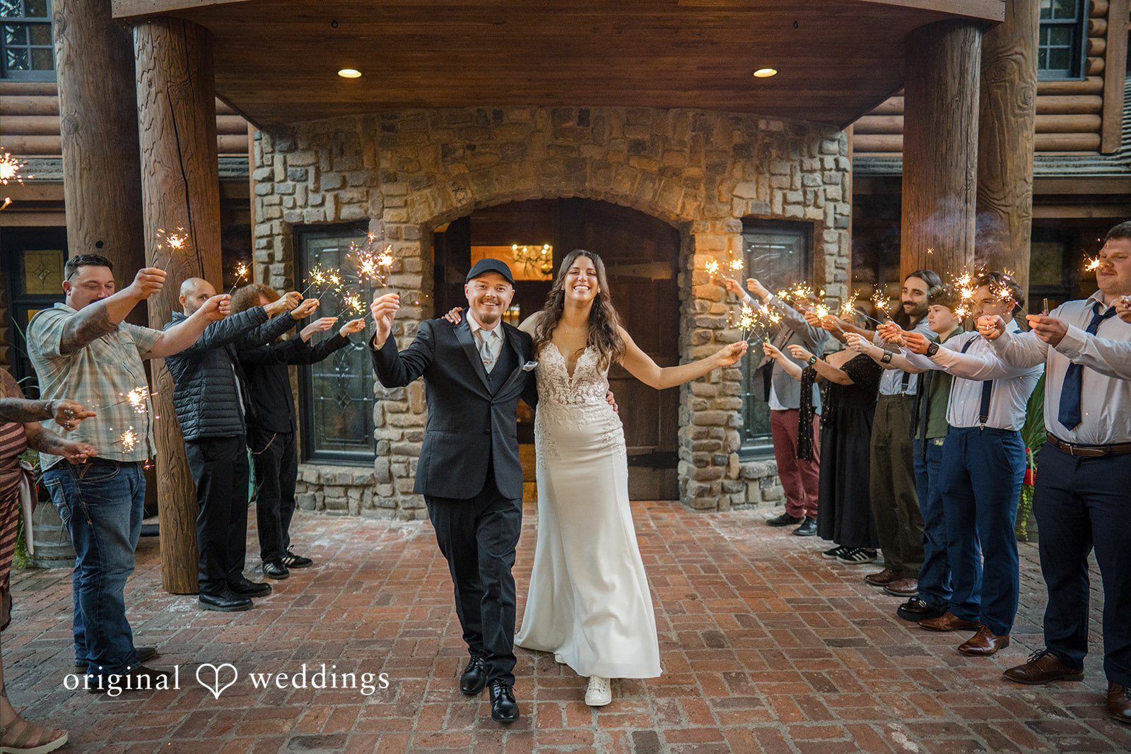 Jade + Nicholas A bride and groom walking through a crowd of guests holding sparklers aloft.