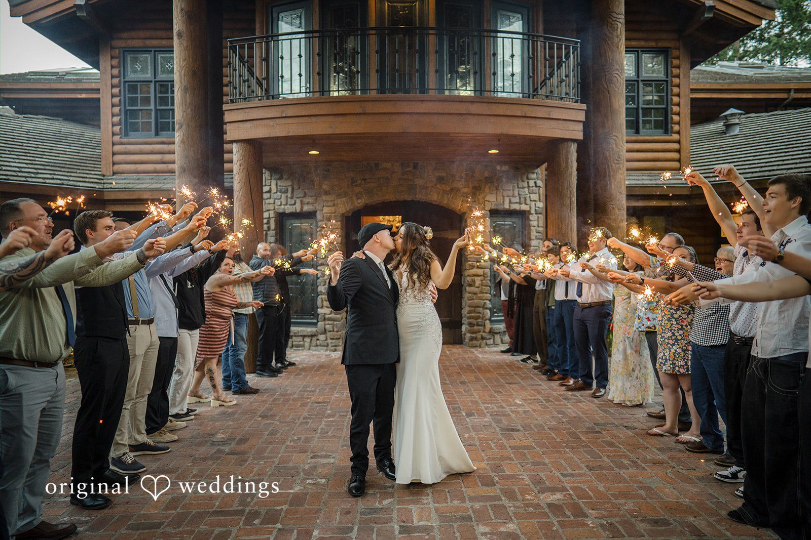 Jade + Nicholas A bride and groom walking down a path lined on both sides by cheering guests.