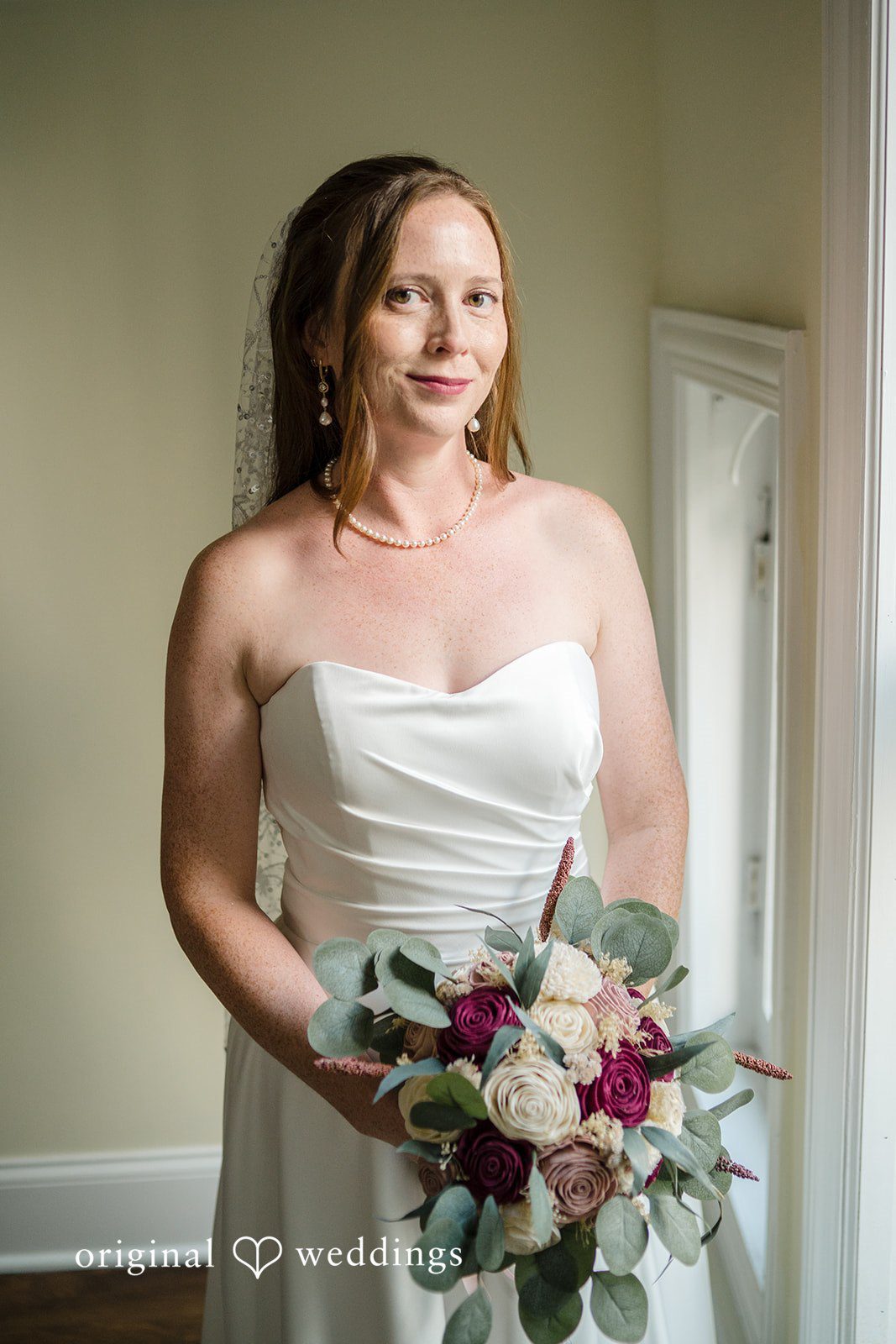 Kimberly + David Smiling bride in a strapless gown holding a bouquet.