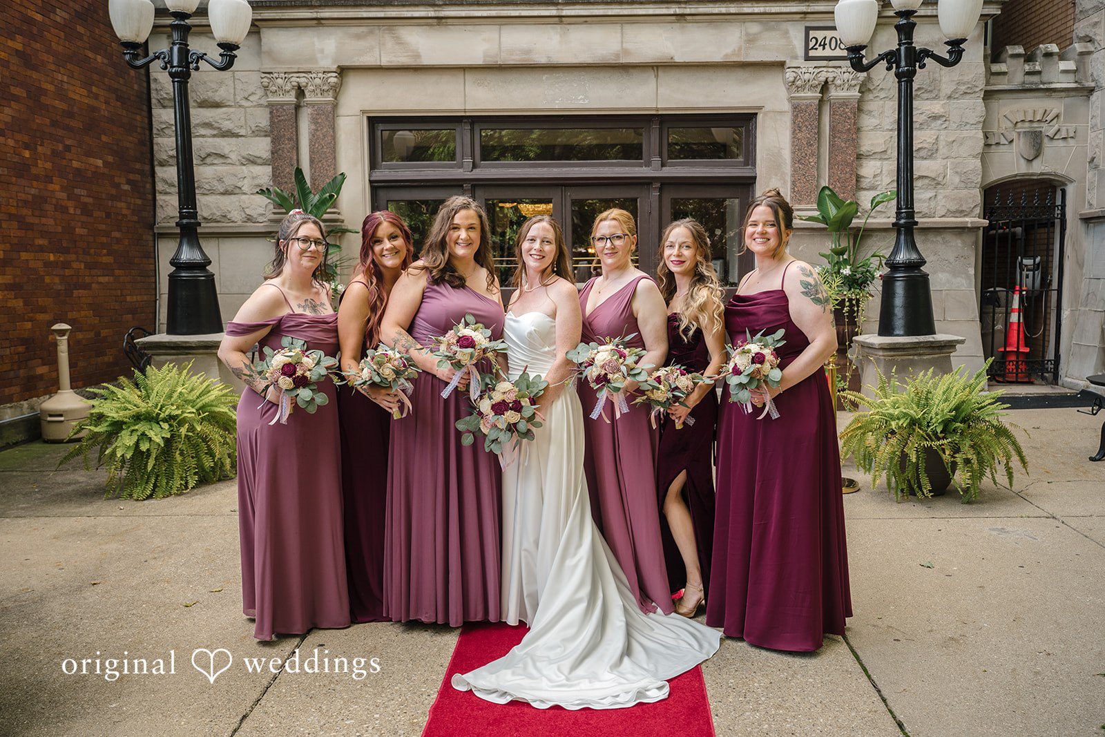 Kimberly + David Bride posing with her bridesmaids in plum gowns.