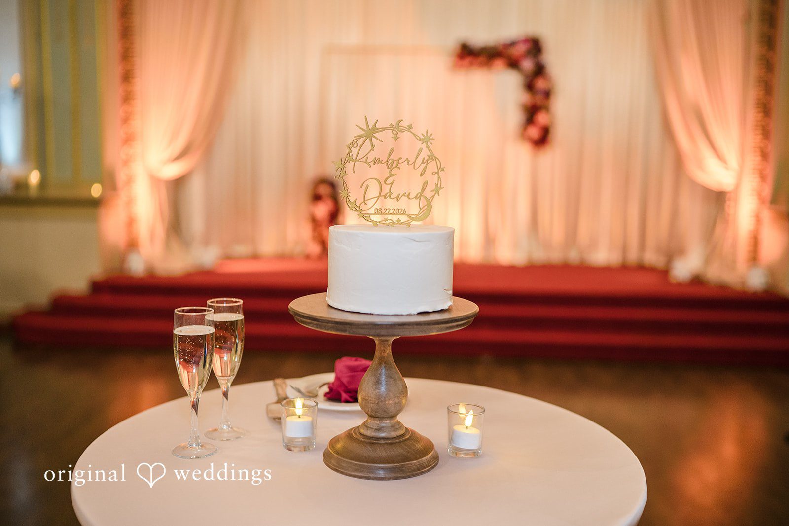 Kimberly + David Simple white tiered wedding cake on a display table.