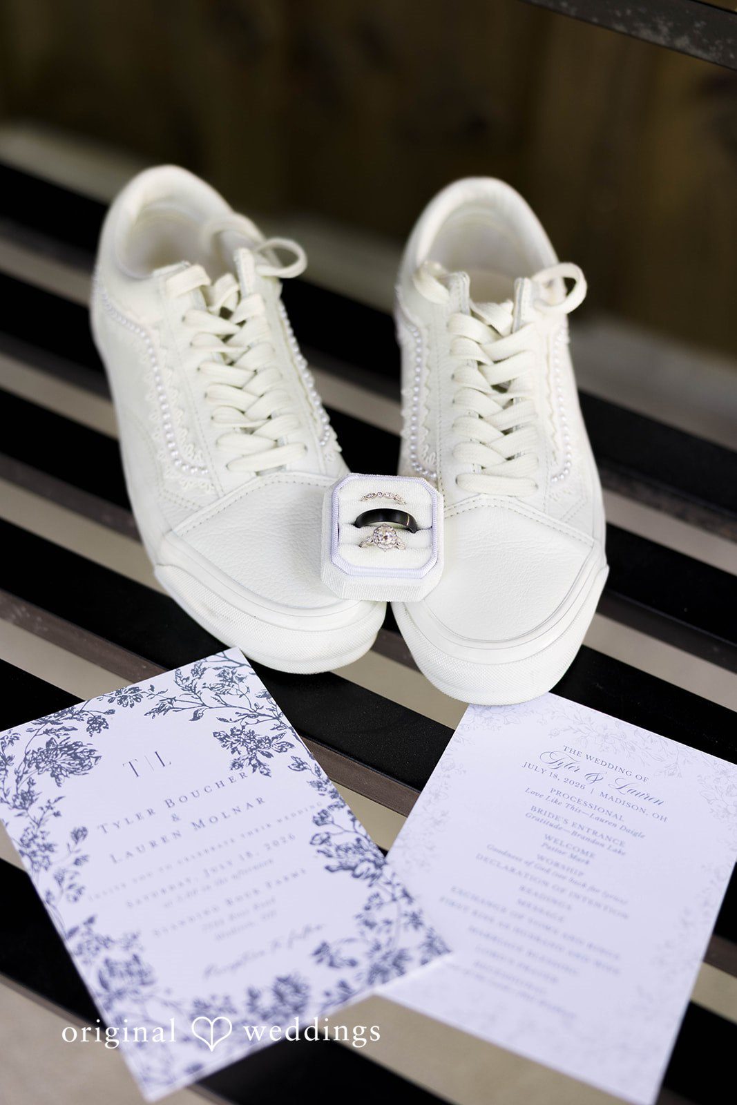 A pair of white sneakers sits alongside a decorated piece of stationery on a flat surface.