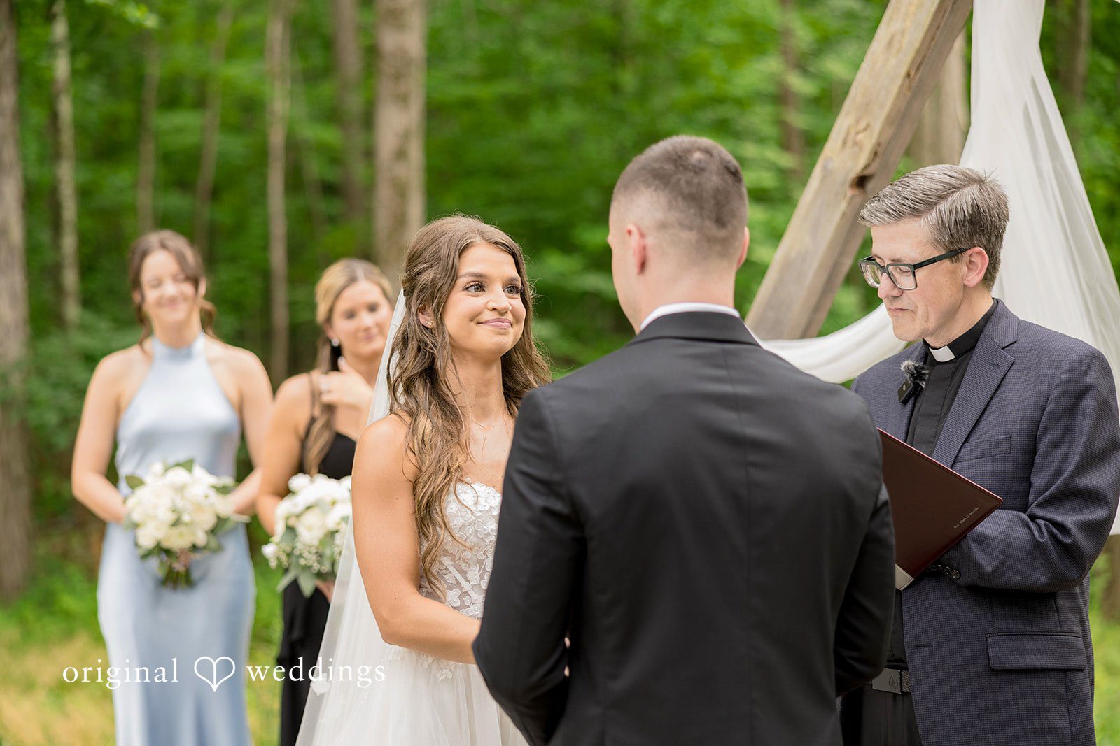 Attendants in light blue dresses stand near men in suits during the ceremony.