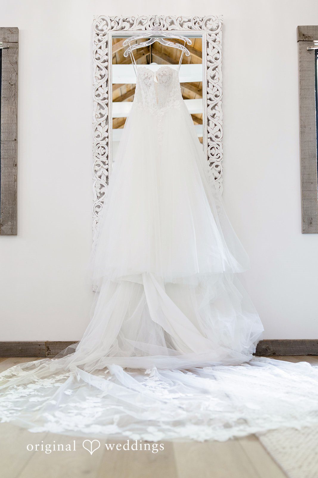 A full-length white wedding dress hangs displayed against a wall.