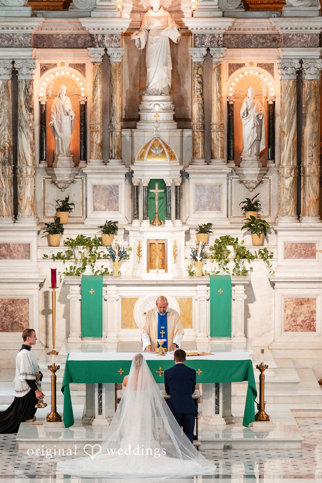 A wedding altar is brightly decorated with white and green floral arrangements.