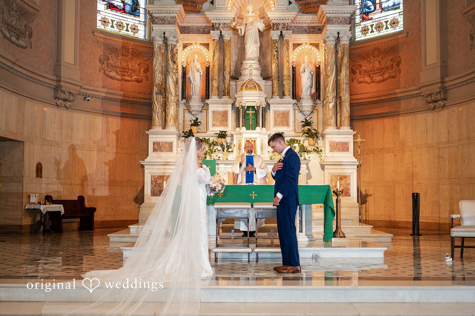A wide view captures a wedding ceremony taking place inside a grand church sanctuary.