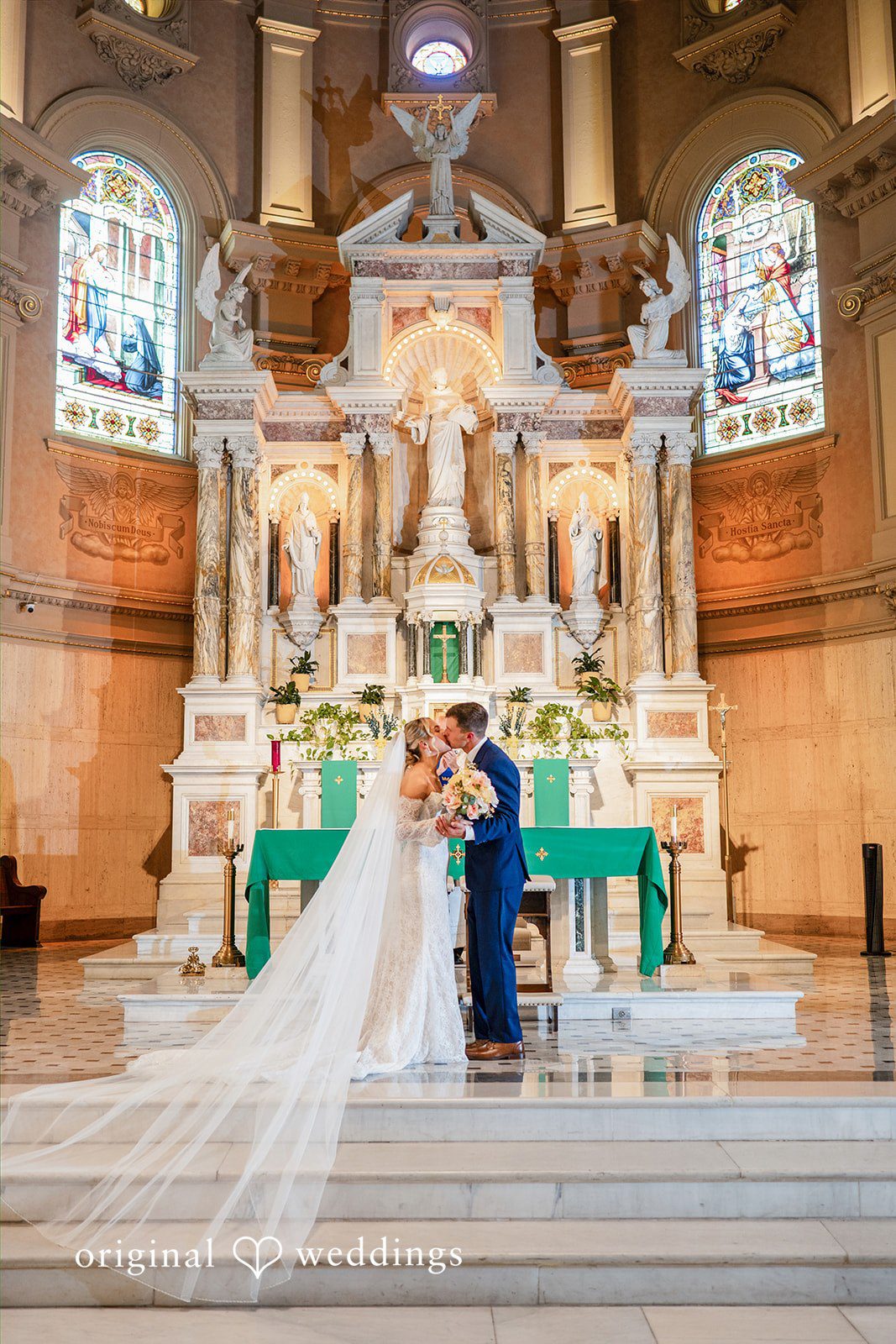 The newlyweds stand together before a highly detailed church altar structure.