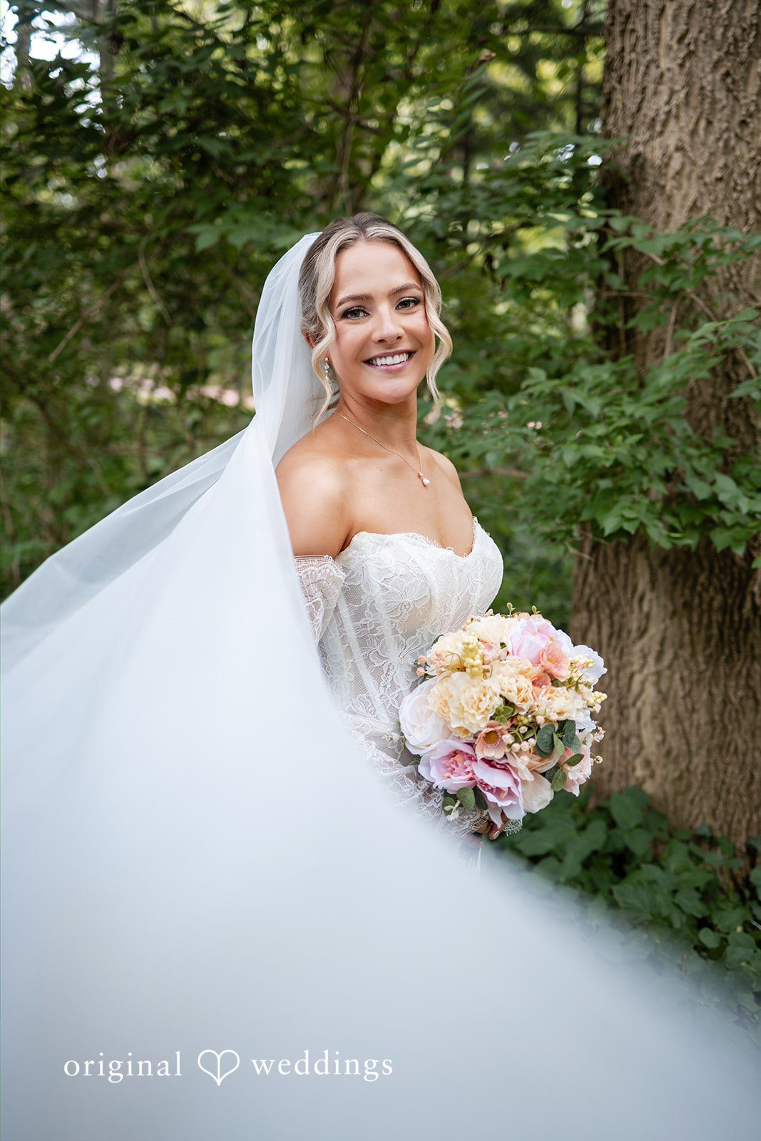A bride poses for a portrait while holding a colorful floral bouquet.