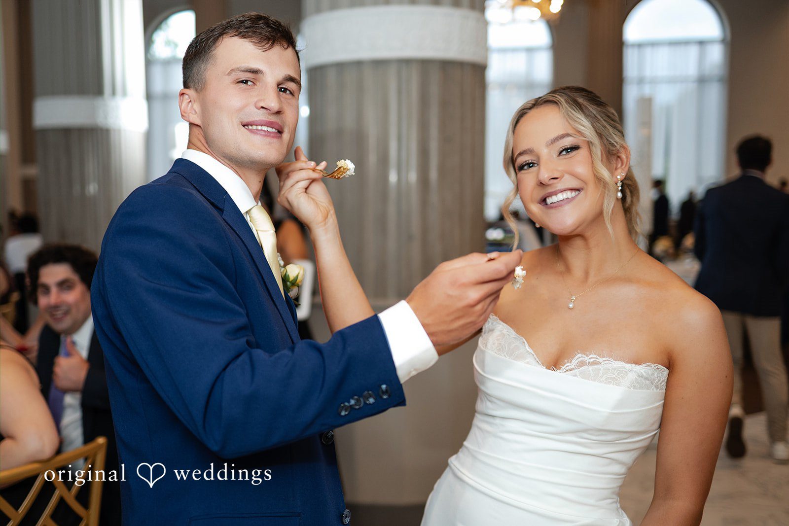 A bride feeds a piece of wedding cake to her groom at the reception.