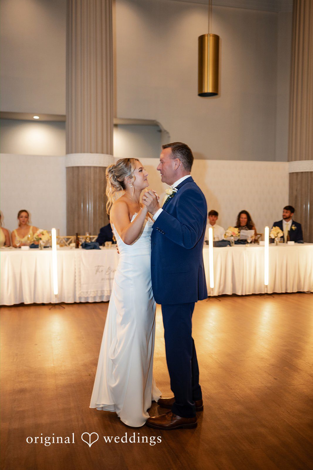 A bride and man share a dance on the floor during the reception.