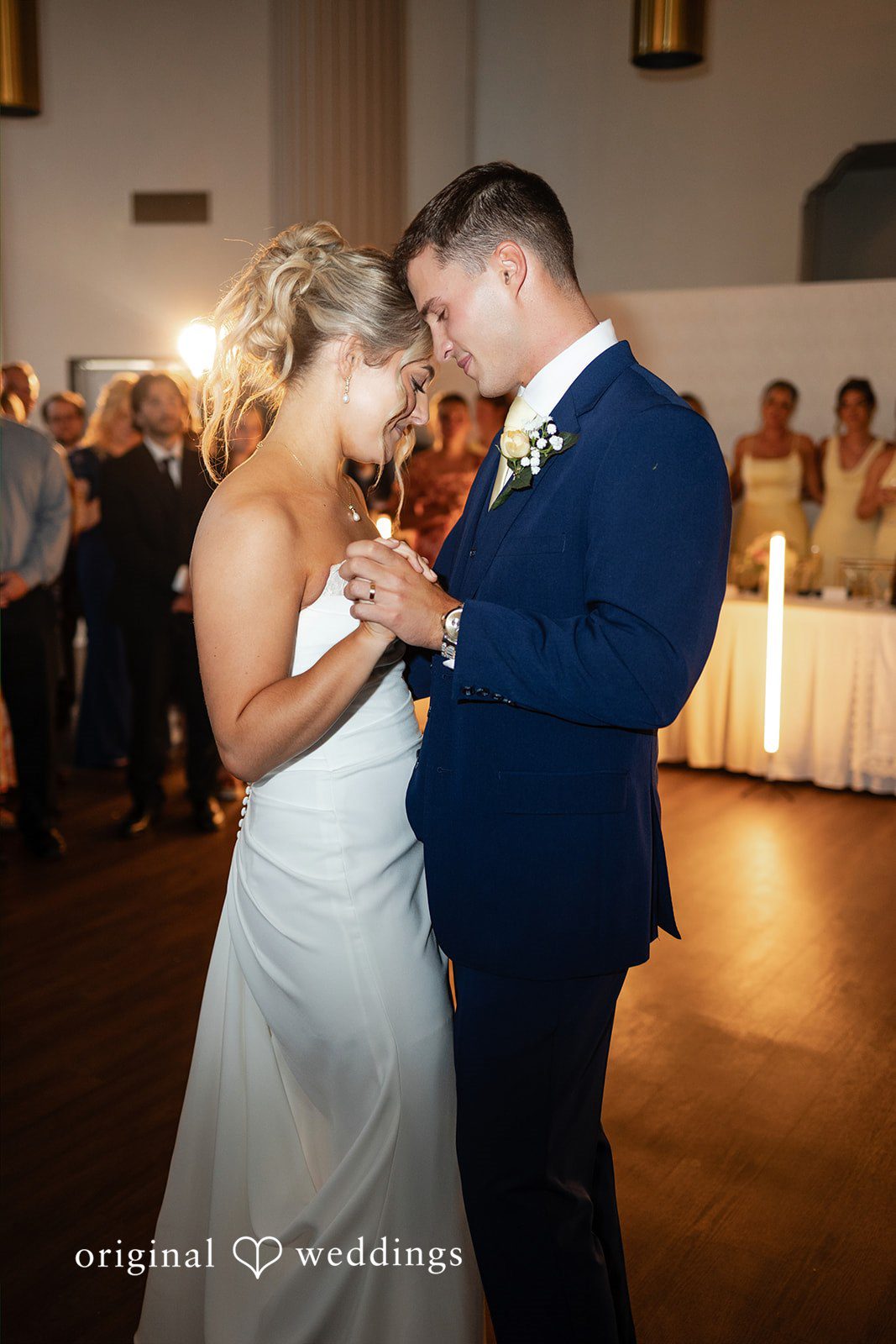 A bride and groom hold hands while sharing an intimate dance at their wedding reception.