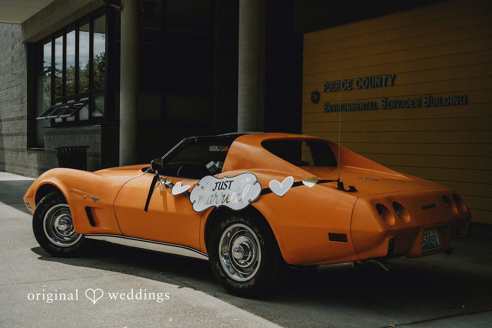 Ashley + Dylan An orange vintage sports car decorated with white flowers for a wedding.