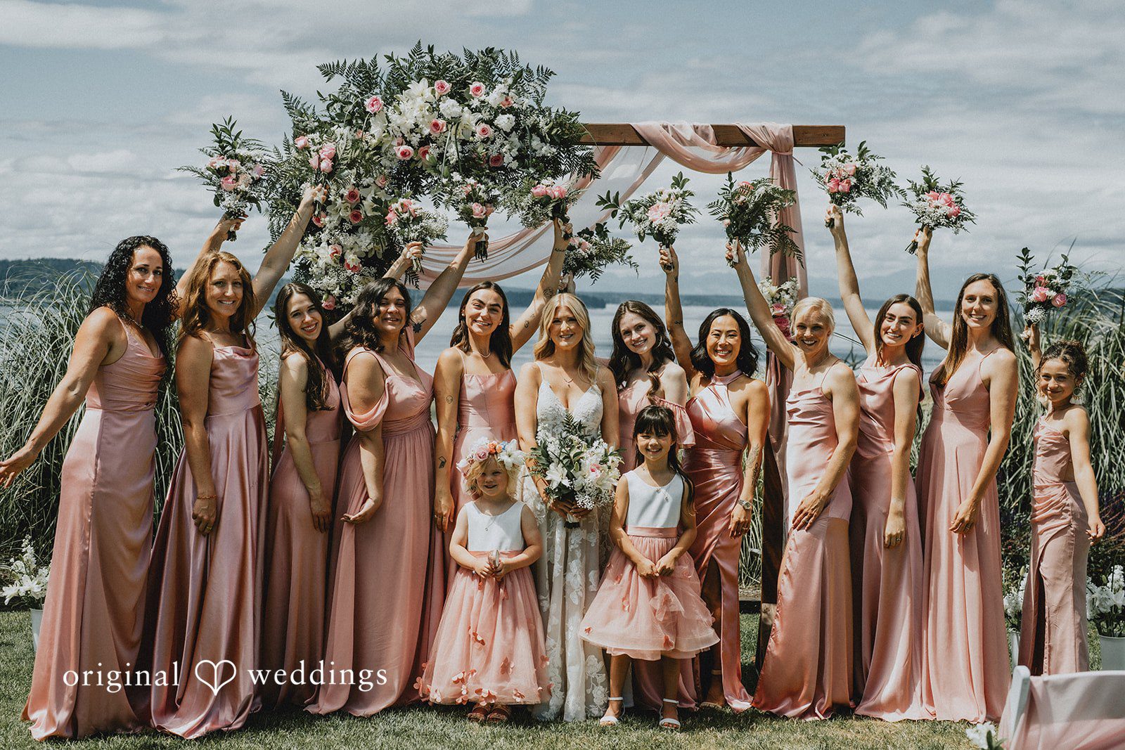 Ashley + Dylan A large group of bridesmaids wearing matching pink dresses standing together.