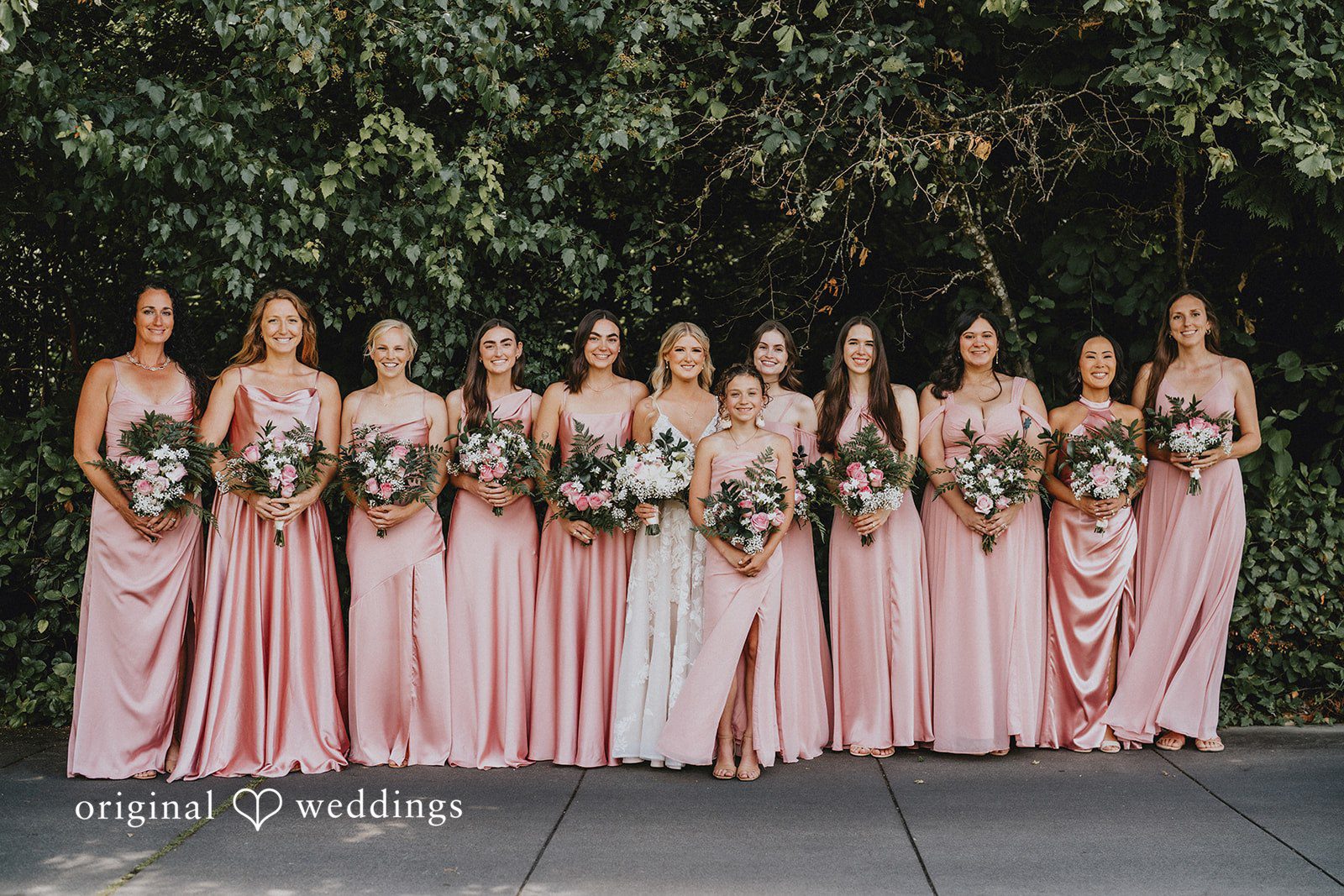 Ashley + Dylan A lineup of bridesmaids in elegant pink gowns holding bouquets.