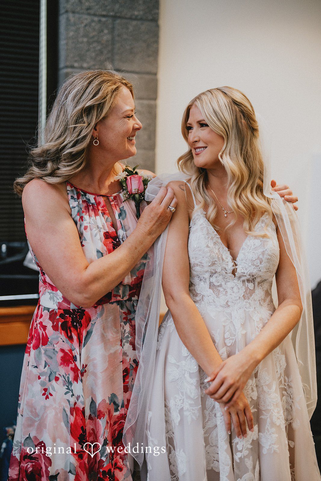 Ashley + Dylan A bride laughing alongside a woman wearing a floral dress.