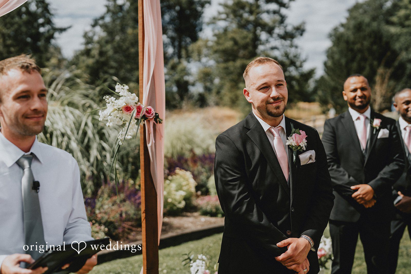 Ashley + Dylan A groom smiling while standing alongside his groomsmen during the ceremony.