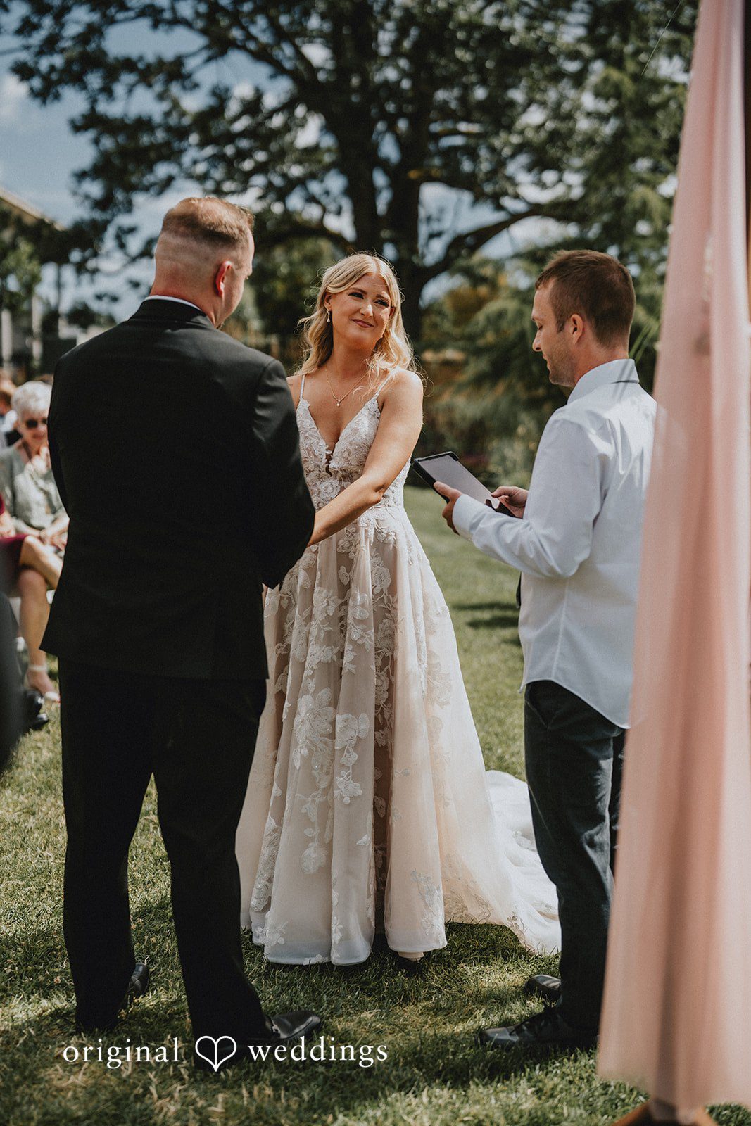 Ashley + Dylan A bride and groom standing under a pink fabric arch during a ceremony.