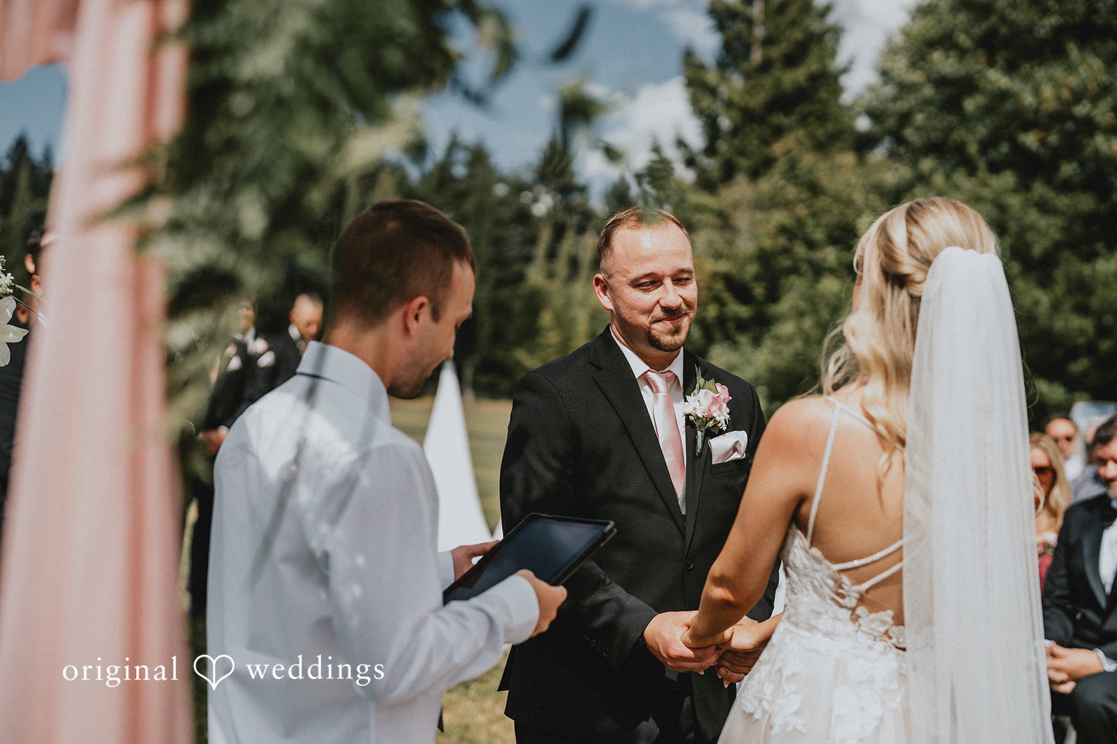 Ashley + Dylan A groom in a suit talking with his bride who is wearing a long white veil.