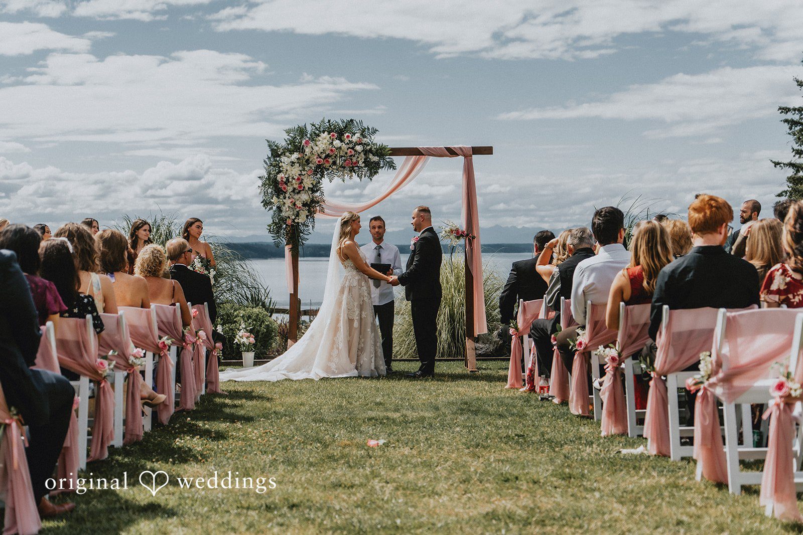 Ashley + Dylan An wedding ceremony showing the couple at the altar with guests seated in chairs.