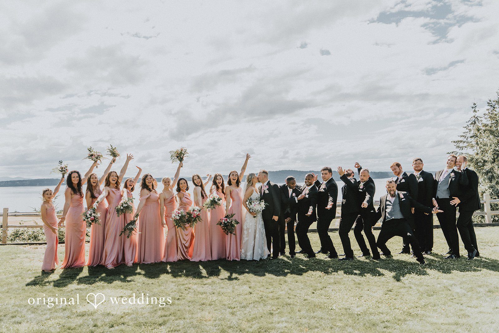 Ashley + Dylan A wedding party posing together for a group photo in an open field.