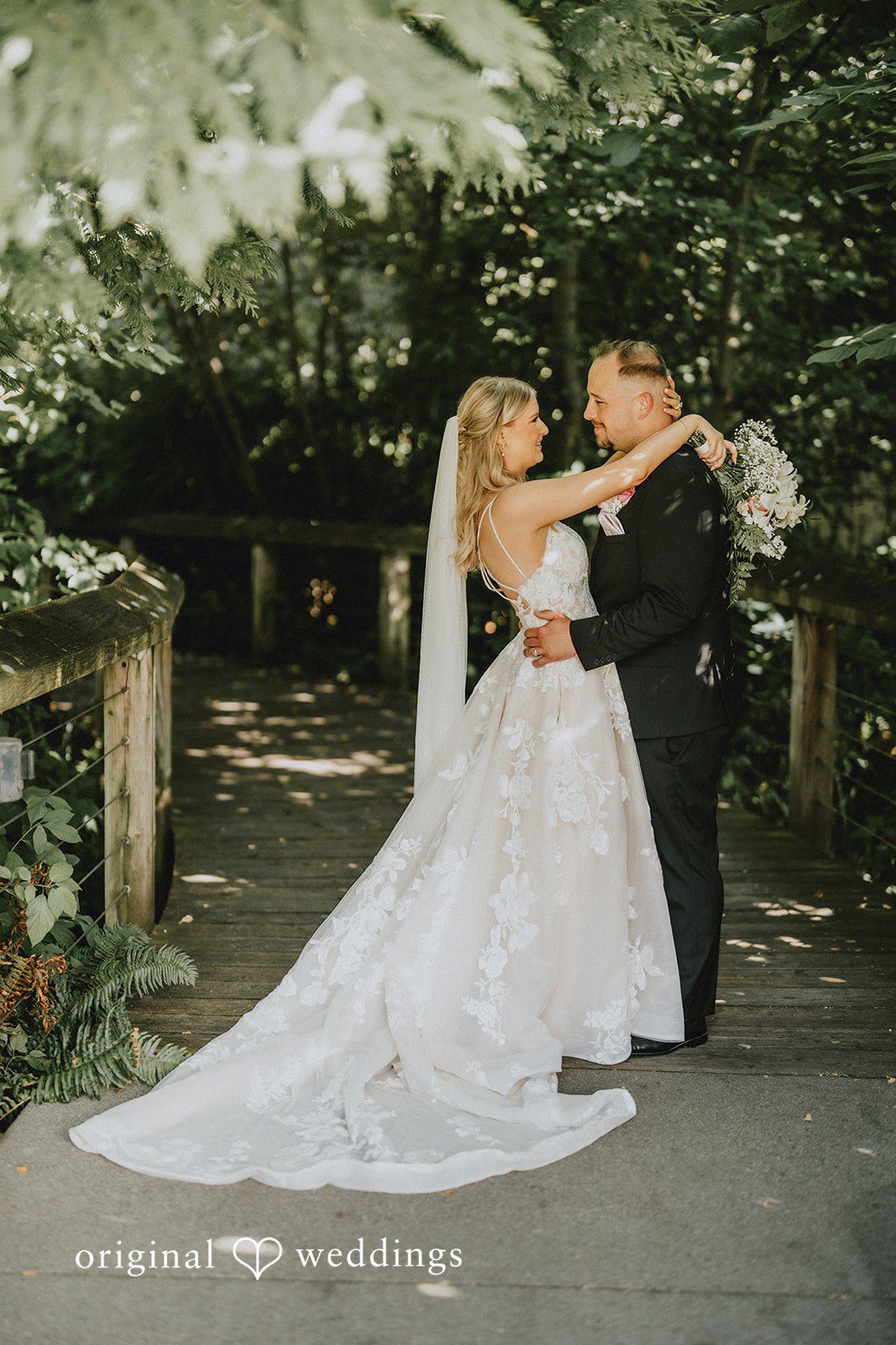 Ashley + Dylan A bride in a long white dress posing on stone steps next to her groom.
