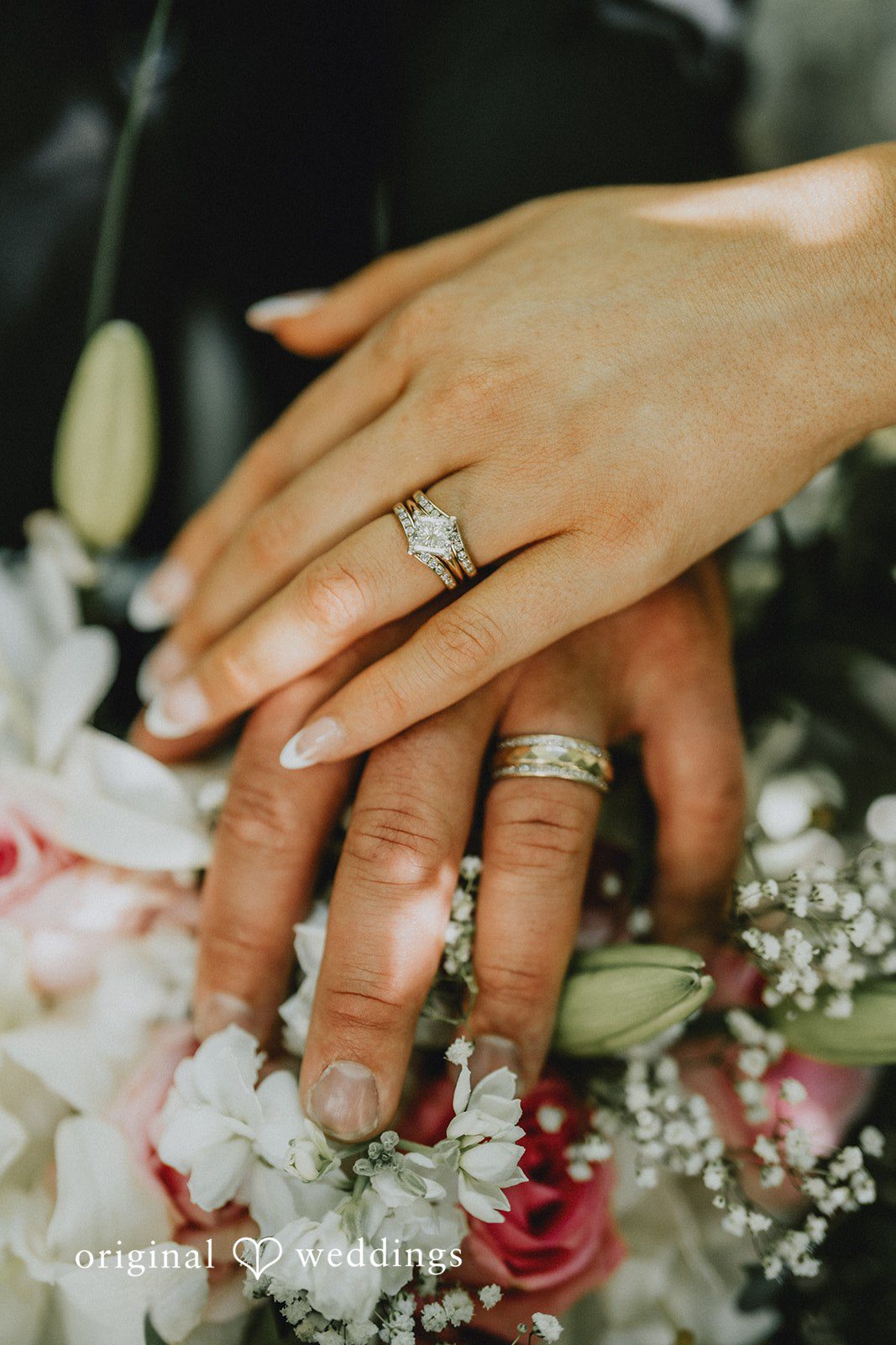 Ashley + Dylan A close-up view of a bride's hand showing off her wedding ring on top of a bouquet.