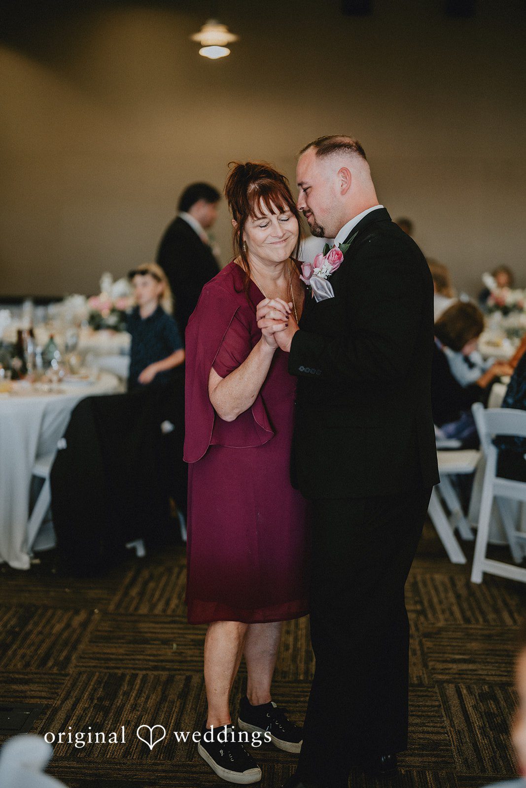 Ashley + Dylan A women in a purple dress smiling and dancing with groom in a dark suit.