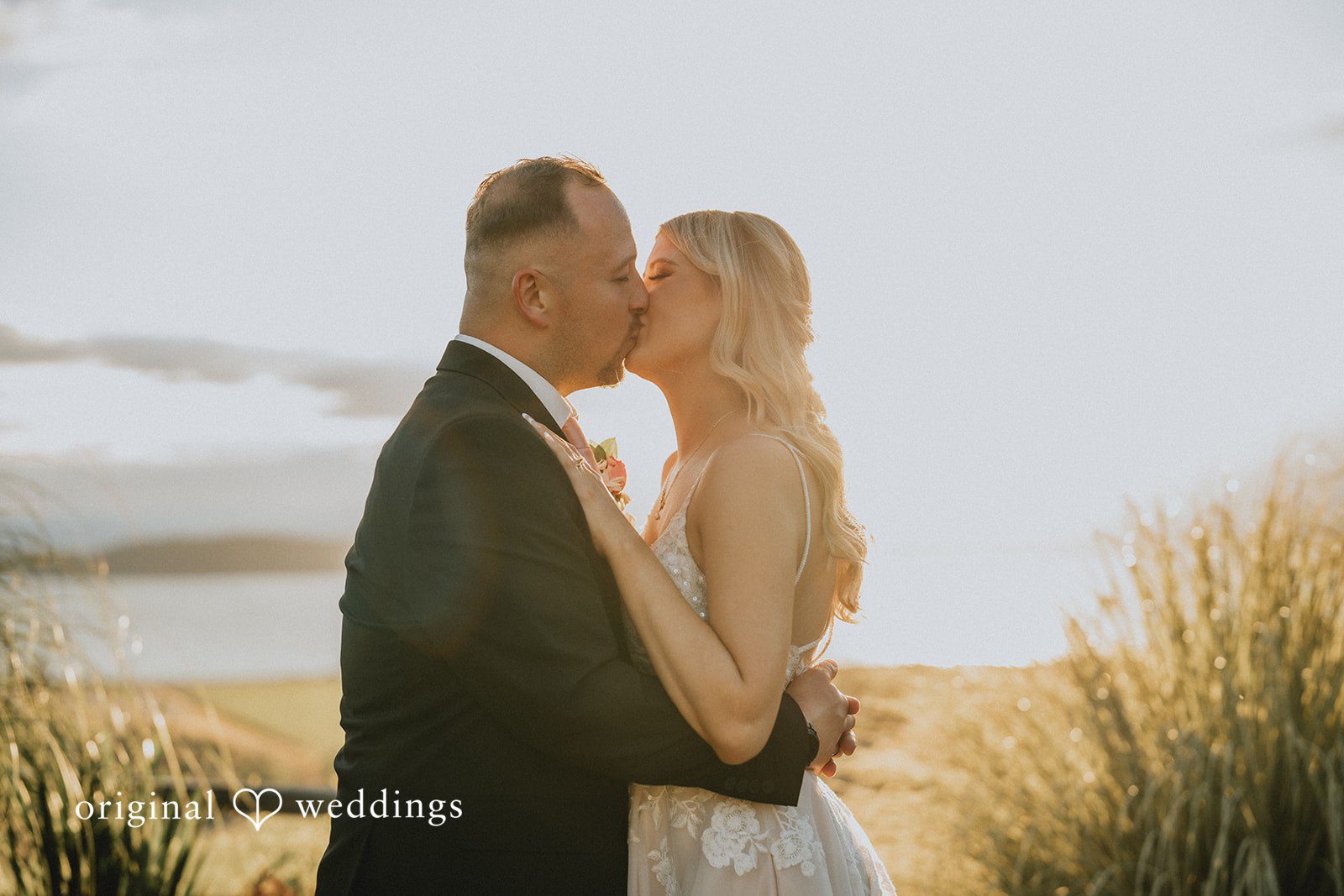 Ashley + Dylan A bride and groom standing close together and kissing each other.