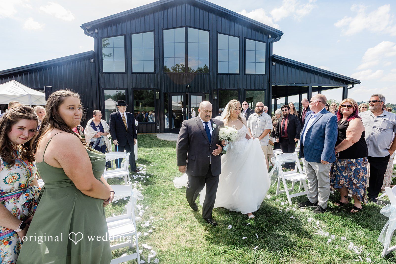 Wedding guests gathered outside a modern black barn venue for an event.