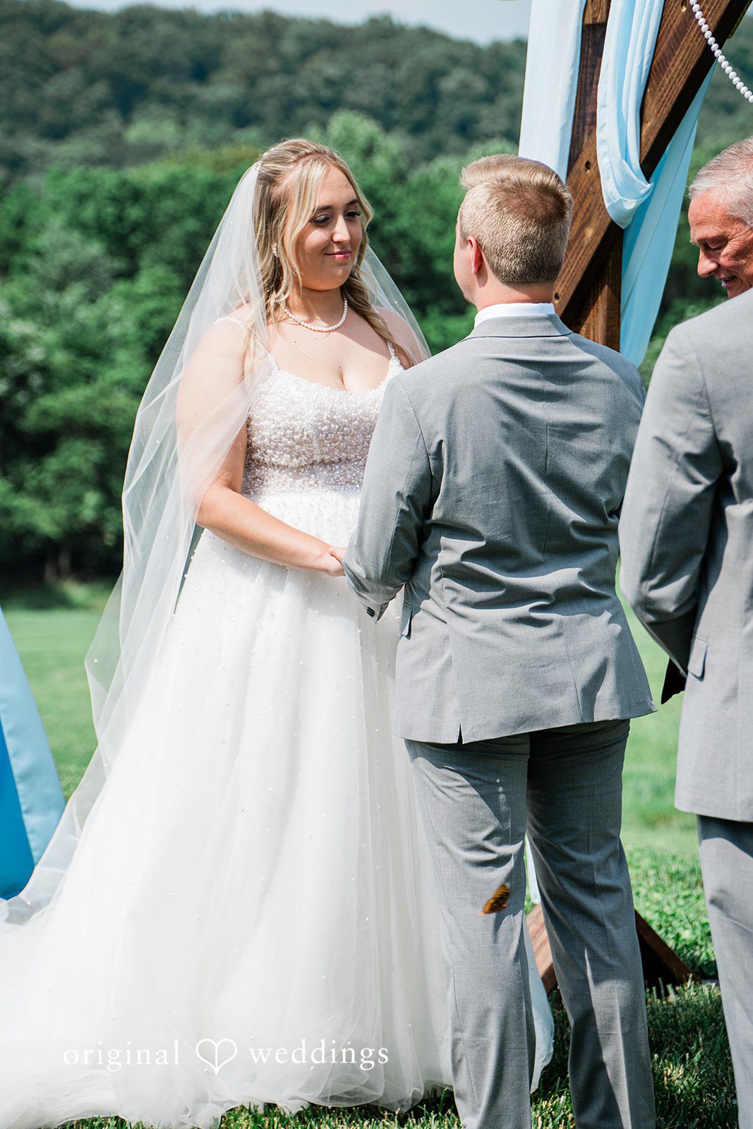 A bride and groom walking together while wearing their wedding attire.