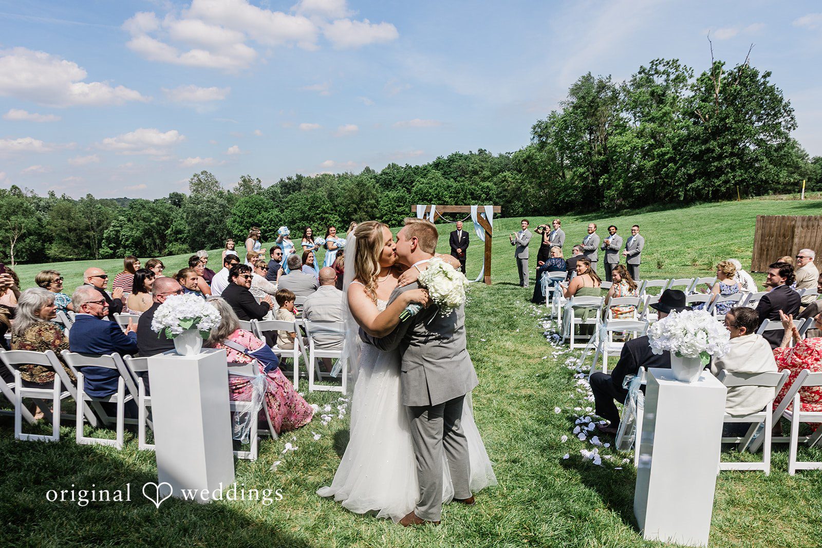 Wedding guests seated in rows facing a decorated altar during an open-air ceremony.