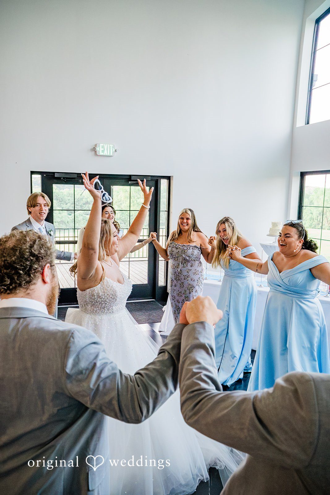 A bride dancing and celebrating with her bridesmaids in light blue dresses.