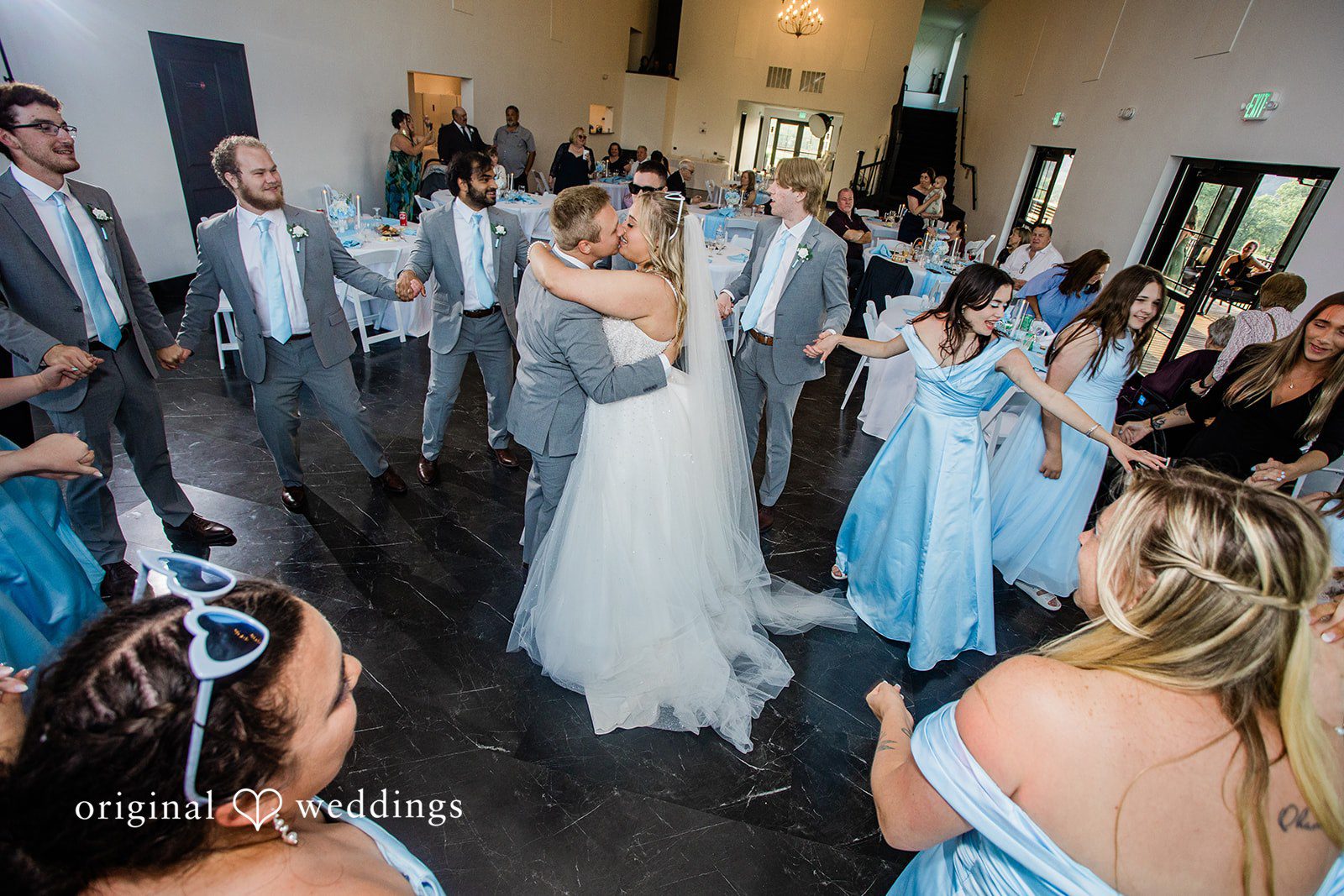 A wide shot of a wedding reception dance floor filled with celebrating guests.