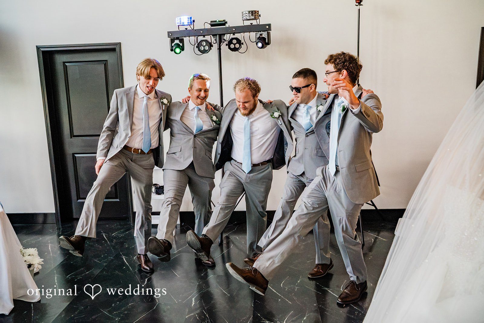 A groom celebrating and posing with his groomsmen inside a modern venue.