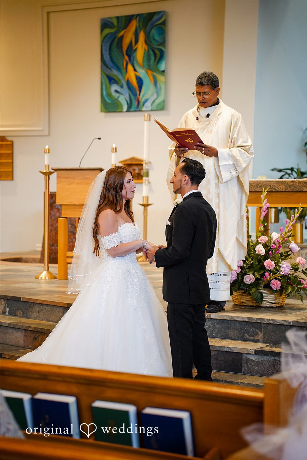 Vincenzo + Kristin A bride and groom standing before a priest at a church altar.