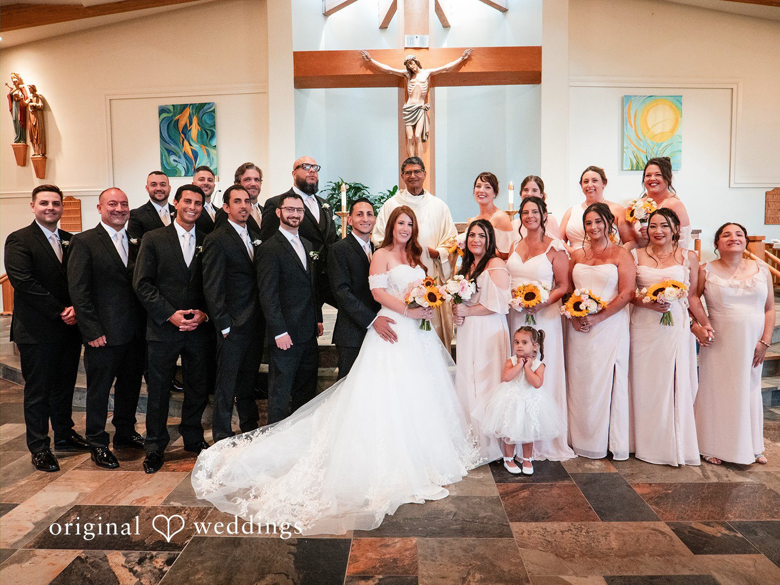 Vincenzo + Kristin A bride and groom posing with a large group of guests inside a church altar area.