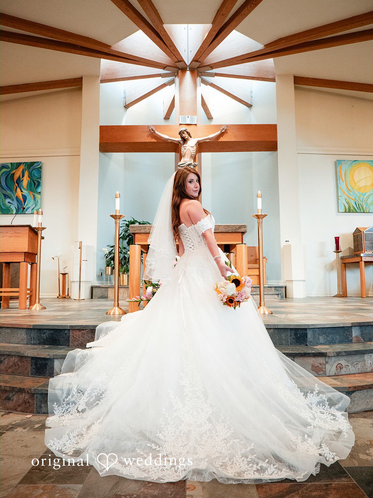 Vincenzo + Kristin A bride in a flowing wedding dress posing inside a church hall.