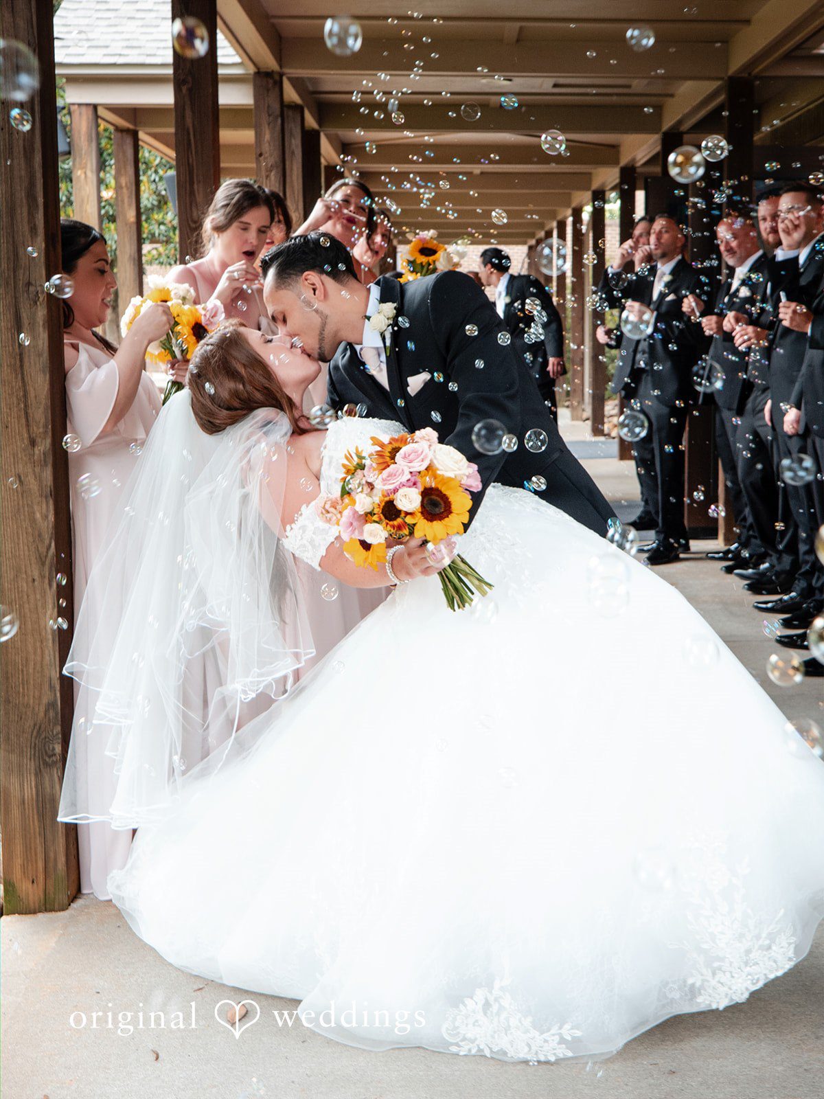 Vincenzo + Kristin A bride in a large white ballgown posing outdoors with her groom.