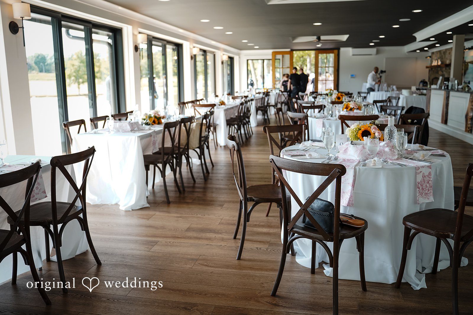 Vincenzo + Kristin An empty dining venue arranged with multiple tables and chairs for a wedding.