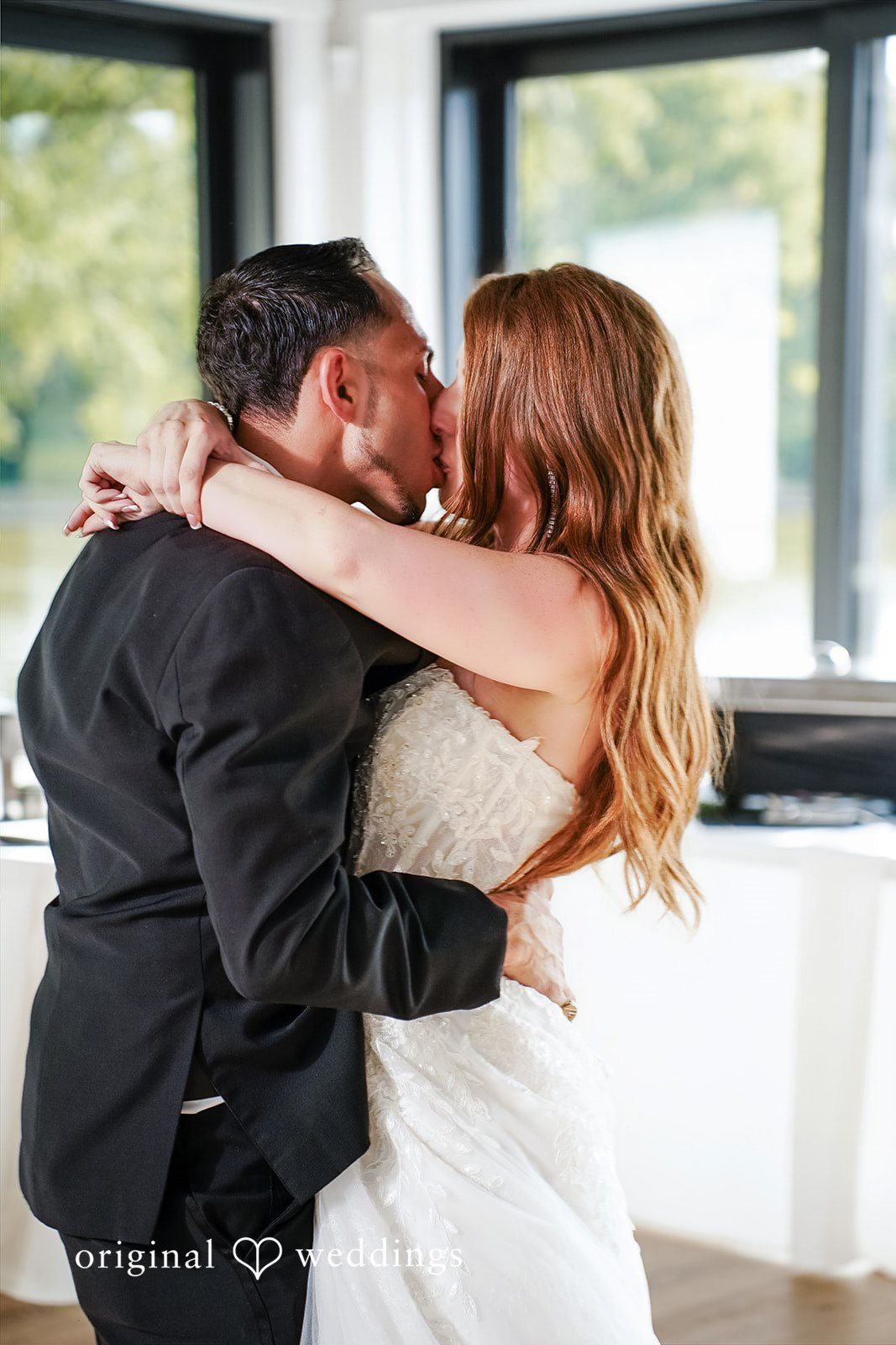 Vincenzo + Kristin A bride and groom share a passionate kiss while embracing during their wedding reception.