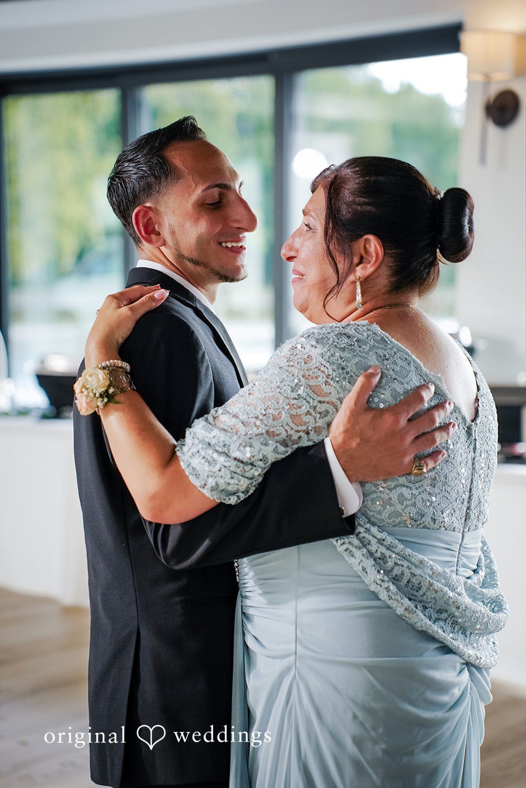 Vincenzo + Kristin A smiling groom in a dark suit shares a slow dance with a woman