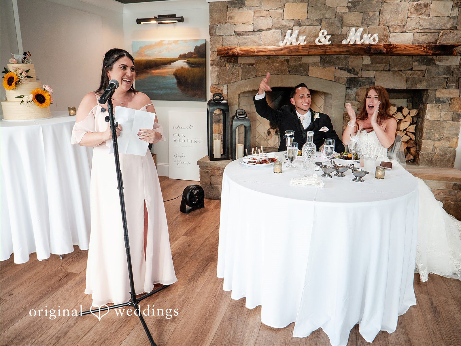 July 11, 2026 – Vincenzo & Kristin – (ID-4669) REVISED 9.6 A decorated wedding reception room featuring a round table with a white tablecloth.
